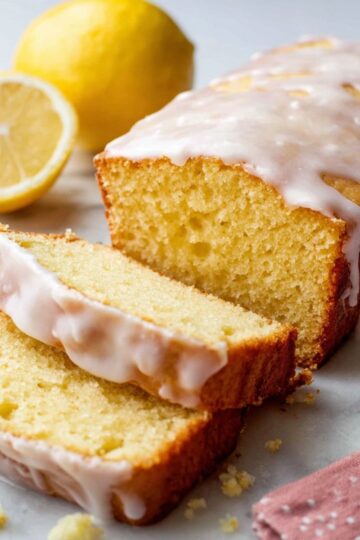Glazed lemon pound cake loaf with slices and yellow lemons