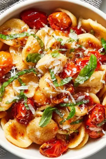 Close up of savory roasted tomato garlic pasta showing blistered tomatoes and melted parmesan.