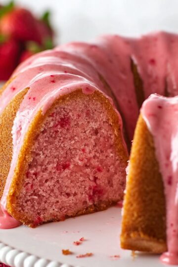 Sliced strawberry pound cake with pink glaze dripping down moist pink crumb
