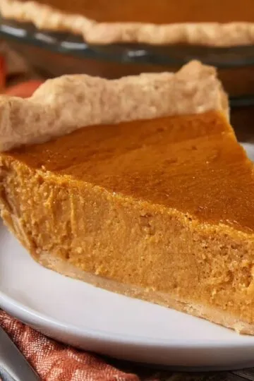 A thick wedge of sweet potato pie with a golden, flaky crimped butter crust.