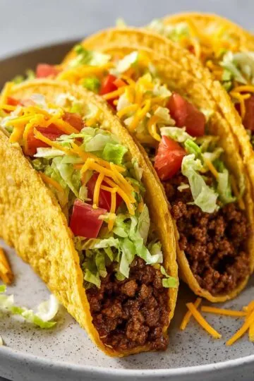 Taco Crock Pot 10 Three hard shell portions of Taco Crock Pot topped with crisp lettuce and cheese.